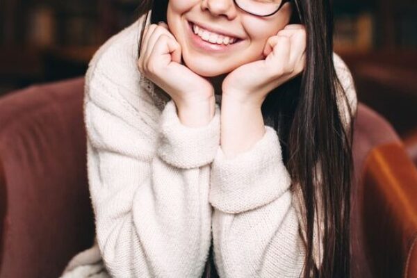 smiling-student-sitting-against-bookshelves-2022-11-03-04-25-20-utc (1)