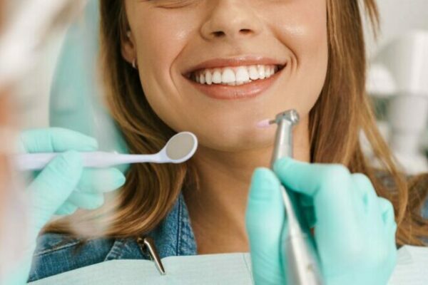 smiling-woman-sitting-in-medical-chair-while-denti-2021-09-03-14-07-45-utc-1-e1653633200669