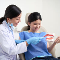 Dentist explaining her patient how to brush teeth